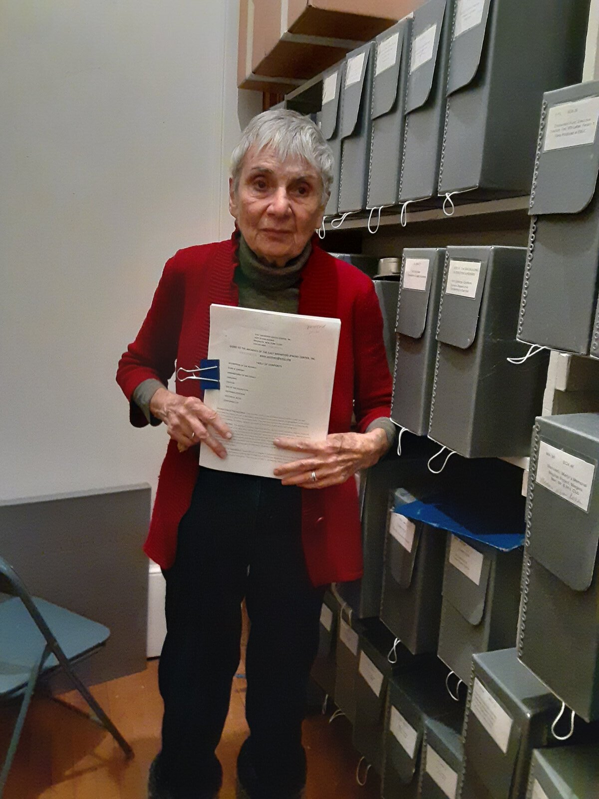 Toby in her archive room, holding a document.